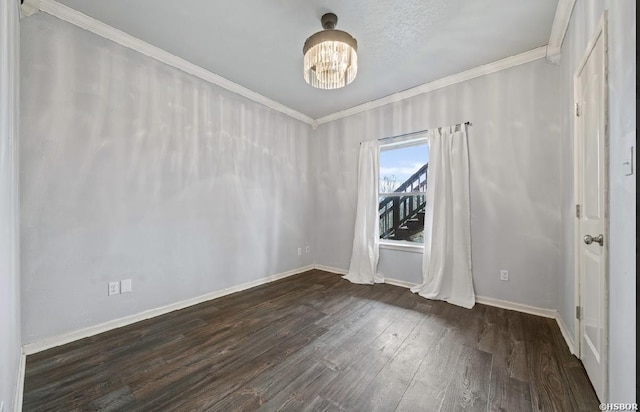 empty room featuring ornamental molding, baseboards, dark wood-style flooring, and a chandelier