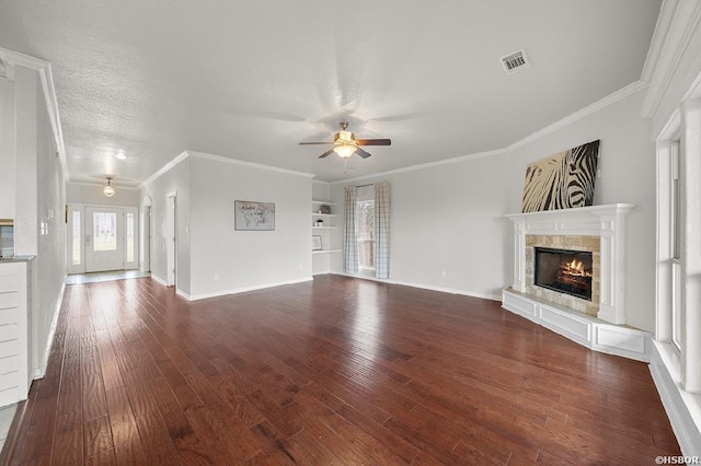 unfurnished living room featuring a tiled fireplace, dark wood finished floors, crown molding, and ceiling fan