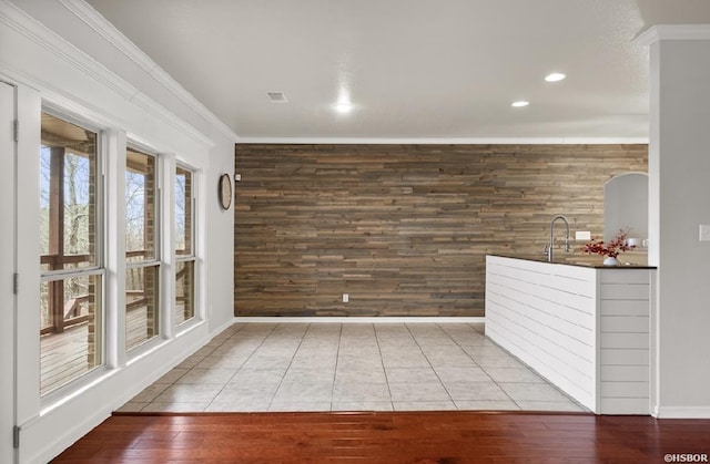 interior space featuring wood finished floors, baseboards, wood walls, and ornamental molding