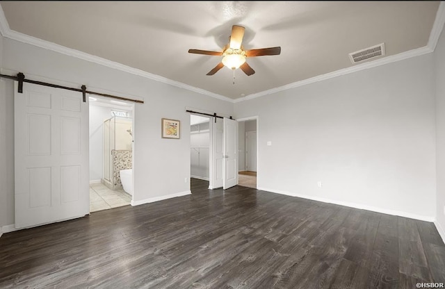 unfurnished bedroom with visible vents, ornamental molding, a barn door, and wood finished floors