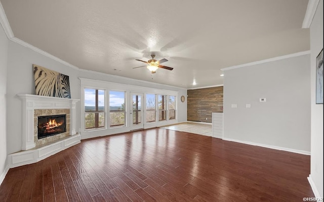 unfurnished living room with wood finished floors, crown molding, ceiling fan, and a premium fireplace