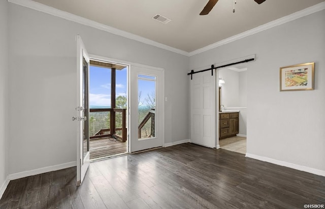 interior space with visible vents, a ceiling fan, wood finished floors, a barn door, and crown molding