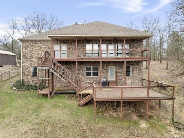 back of property with a lawn, fence, stairway, a wooden deck, and brick siding