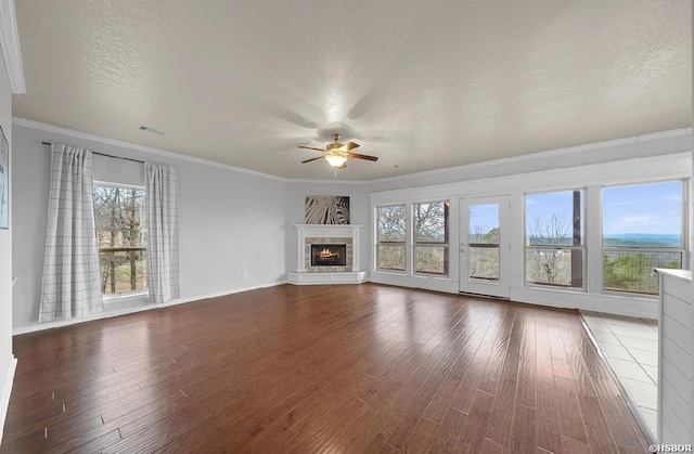 unfurnished living room with a healthy amount of sunlight, wood finished floors, and a ceiling fan