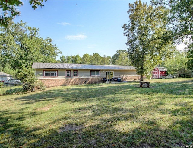 ranch-style house featuring an outbuilding, a front yard, metal roof, fence, and a shed