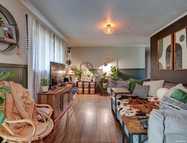 living area with wainscoting, wood finished floors, and crown molding