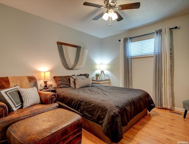 bedroom featuring baseboards, visible vents, ceiling fan, a textured ceiling, and light wood-type flooring