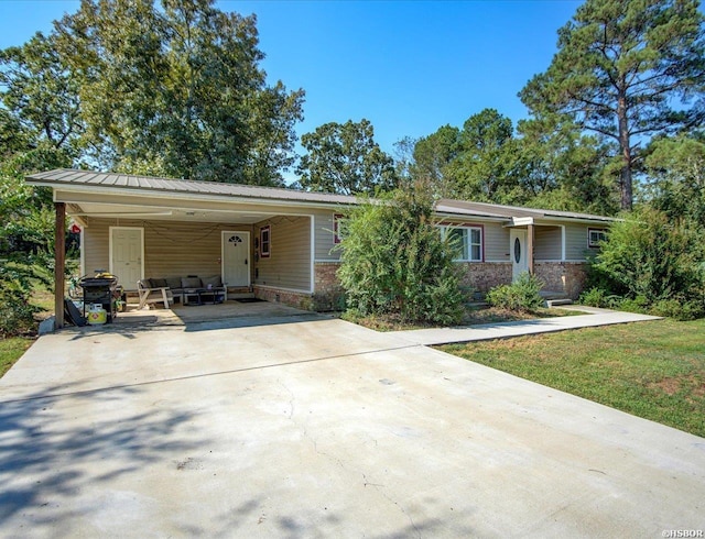 view of front of house featuring brick siding, concrete driveway, a front yard, metal roof, and a carport