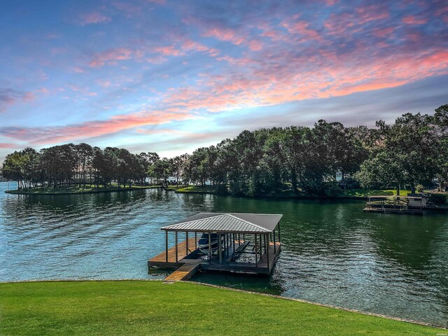 view of dock with a water view, a lawn, and boat lift