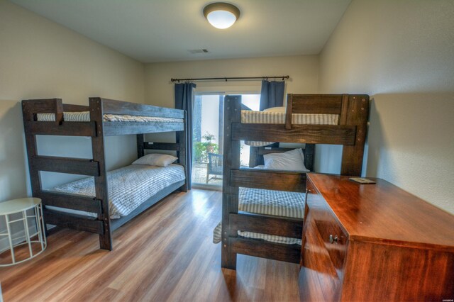 bedroom with access to outside, visible vents, and wood finished floors