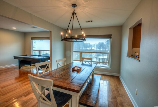 dining area featuring an inviting chandelier, baseboards, visible vents, and wood finished floors