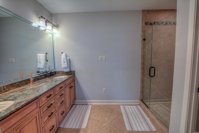 bathroom featuring double vanity, a stall shower, baseboards, tile patterned floors, and a sink