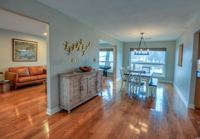 dining space featuring a chandelier, wood finished floors, and baseboards