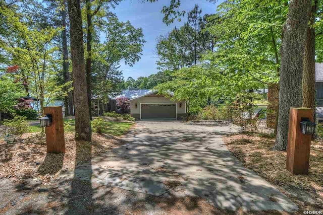 view of front facade with driveway, an attached garage, and fence