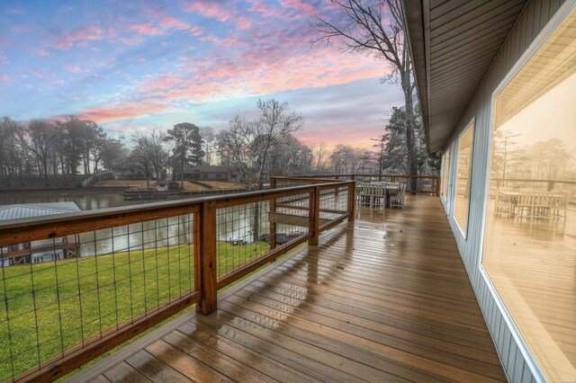 wooden terrace with a water view and a lawn