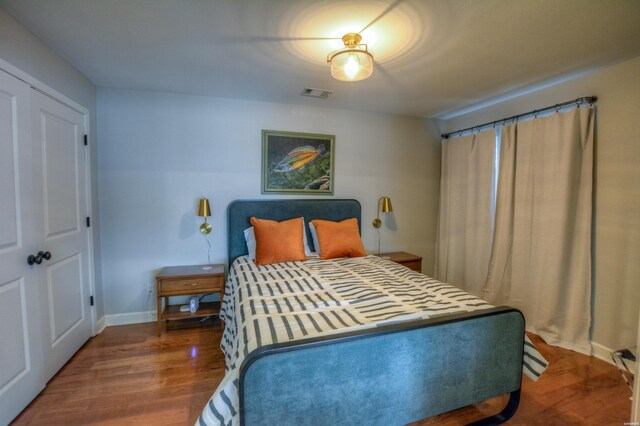 bedroom with wood finished floors, visible vents, and baseboards