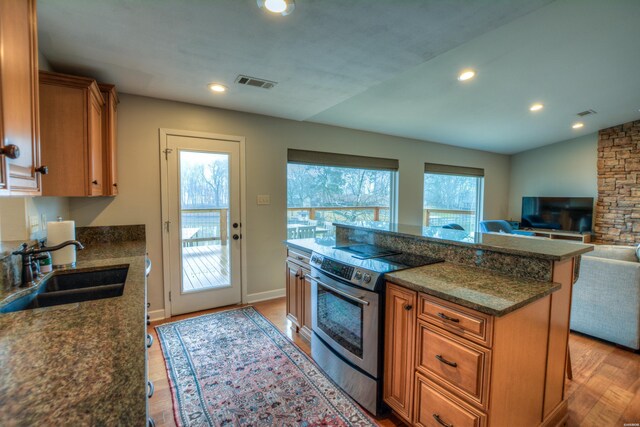 kitchen with light wood finished floors, visible vents, open floor plan, stainless steel electric range, and a sink