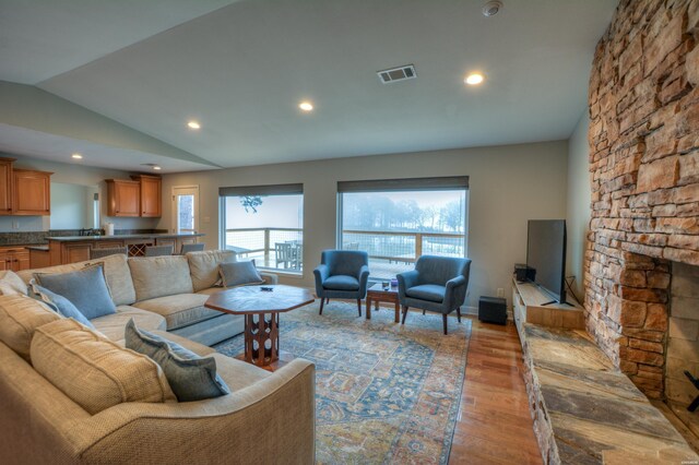 living room with light wood finished floors, lofted ceiling, recessed lighting, visible vents, and baseboards