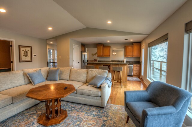 living room with recessed lighting, vaulted ceiling, and light wood finished floors