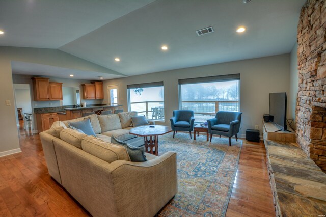 living room with visible vents, lofted ceiling, light wood-style flooring, a fireplace, and recessed lighting