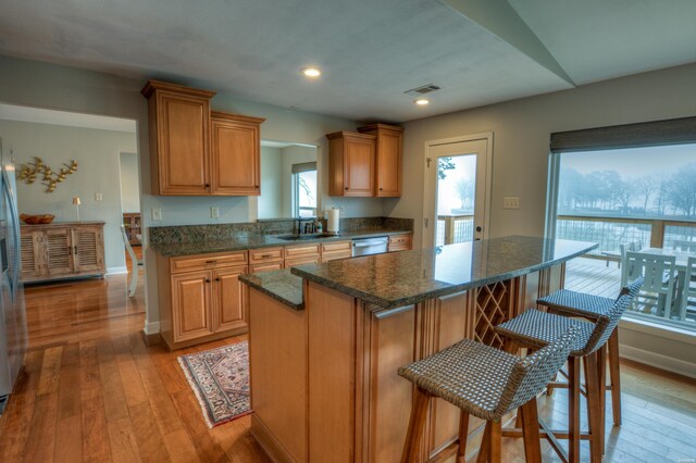 kitchen featuring stainless steel appliances, visible vents, brown cabinetry, a sink, and a kitchen island