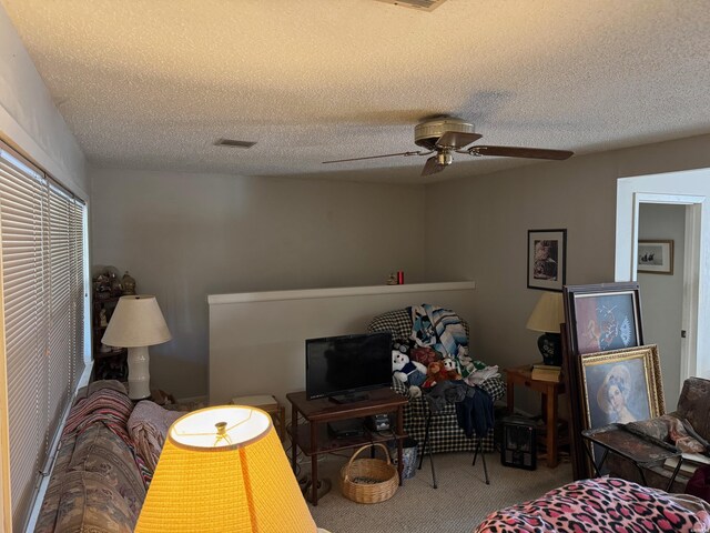 carpeted bedroom with visible vents, ceiling fan, and a textured ceiling