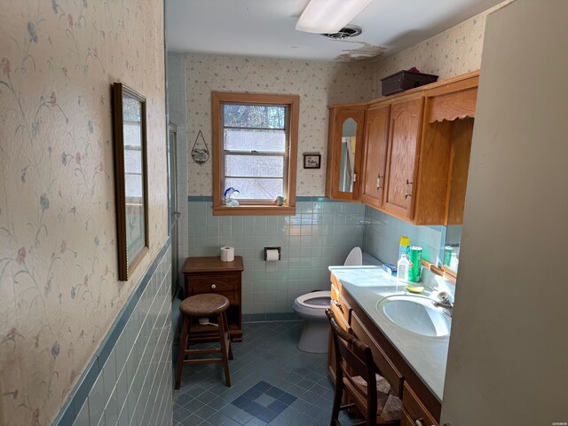 bathroom with wallpapered walls, tile patterned floors, a wainscoted wall, and vanity