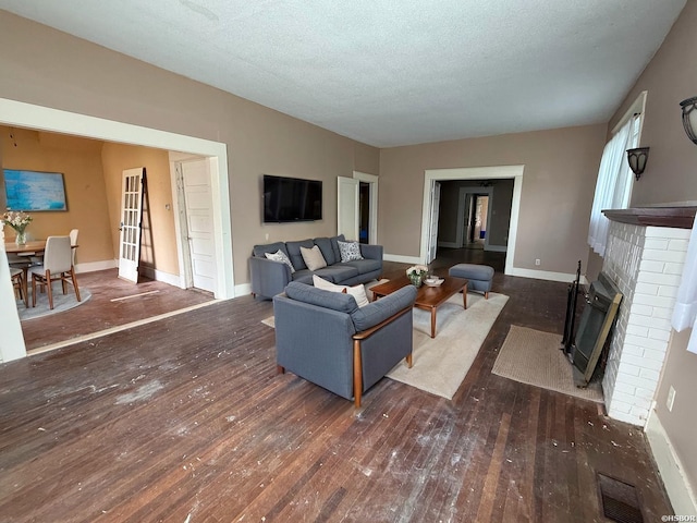 801 Crittenden St, Arkadelphia, AR 71923 - living room featuring wood-type flooring, baseboards, a fireplace, and a textured ceiling
