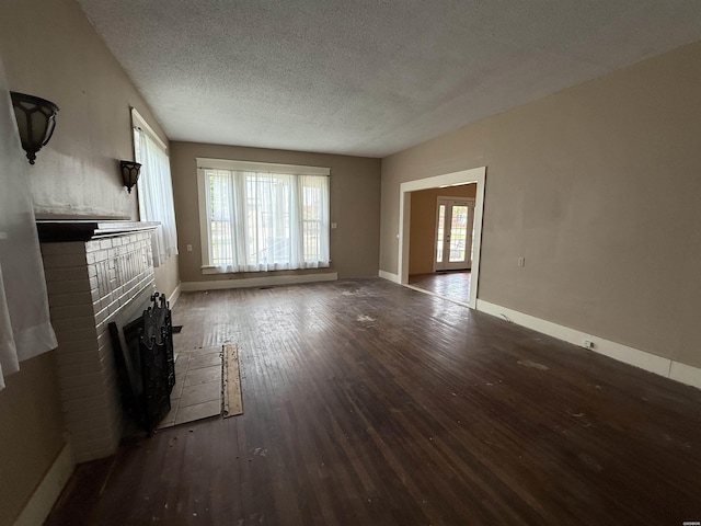801 Crittenden St, Arkadelphia, AR 71923 - unfurnished living room with a brick fireplace, wood finished floors, a textured ceiling, and baseboards