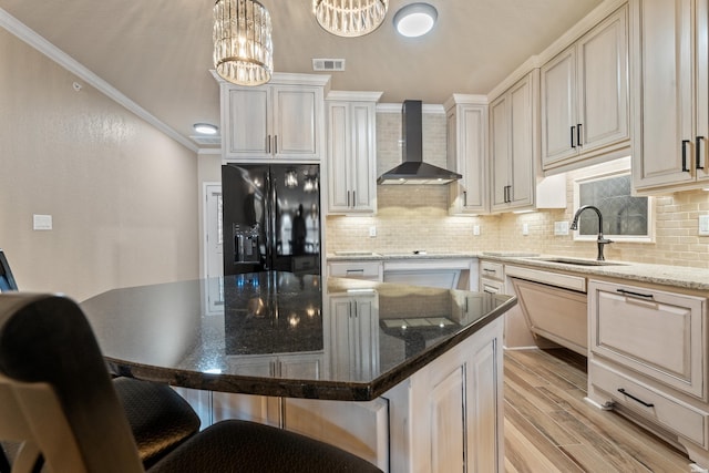 kitchen with visible vents, crown molding, wall chimney range hood, black fridge, and a sink