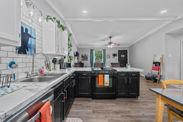 kitchen with white cabinets, black electric range oven, a peninsula, light countertops, and a sink