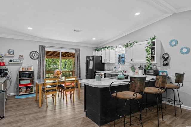 kitchen with a breakfast bar, light countertops, visible vents, white cabinets, and black appliances