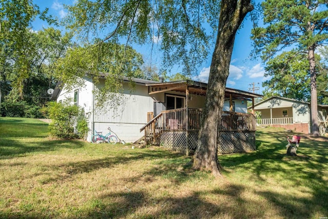 rear view of property featuring a lawn, a wooden deck, and stairs