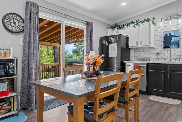 dining room with light wood-type flooring and crown molding