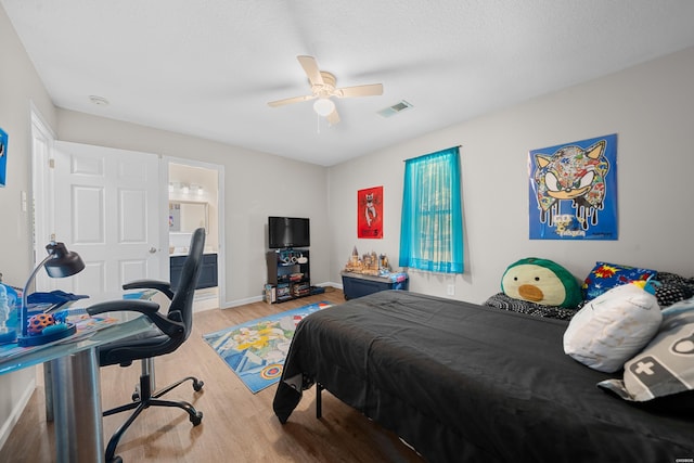 bedroom with light wood finished floors, visible vents, ceiling fan, ensuite bath, and baseboards