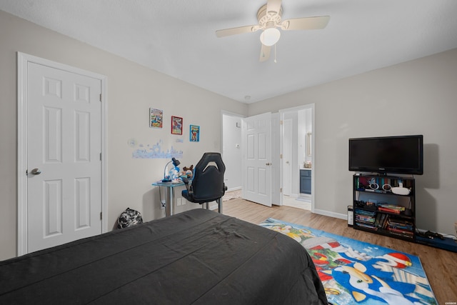 bedroom with a ceiling fan, baseboards, wood finished floors, and ensuite bathroom