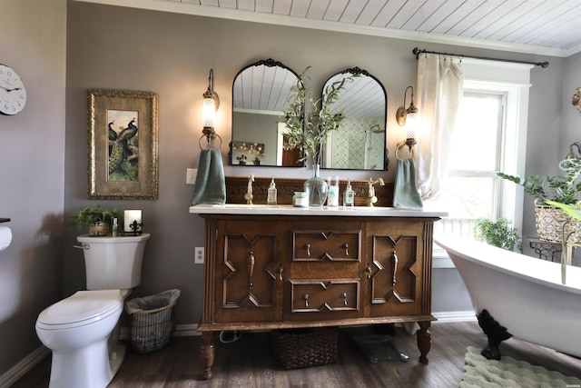 bathroom featuring baseboards, toilet, ornamental molding, wood finished floors, and a soaking tub