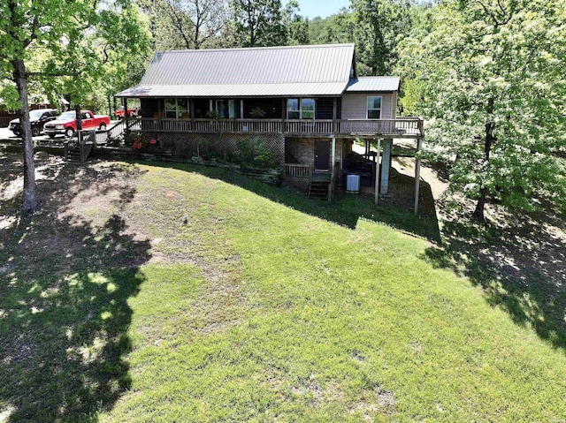 view of front of home featuring metal roof, a deck, a front yard, and stairway