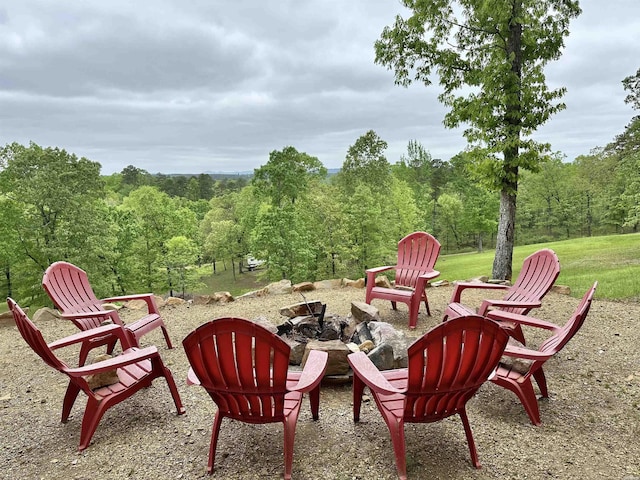 view of patio with a wooded view and an outdoor fire pit
