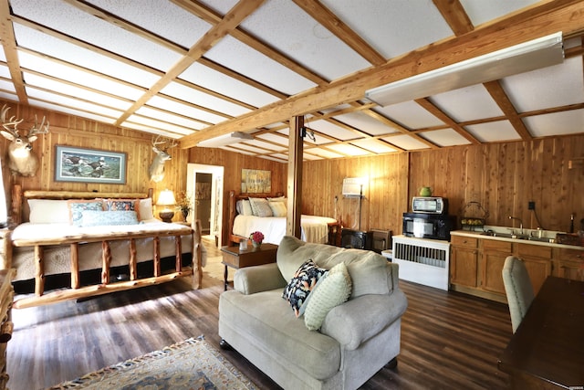 bedroom with dark wood finished floors, wooden walls, beam ceiling, and a sink