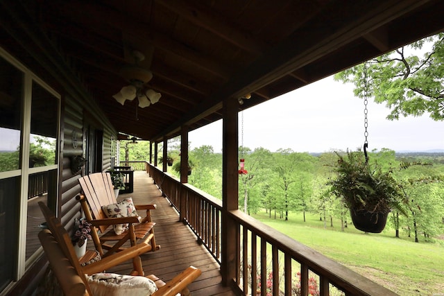 wooden deck with a rural view, a ceiling fan, and a yard