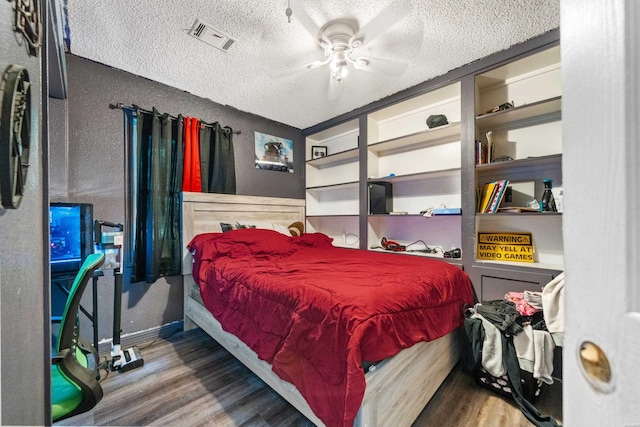 bedroom with a textured ceiling, wood finished floors, and visible vents