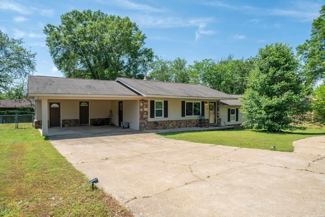 single story home with driveway, fence, a front lawn, stone siding, and an attached carport