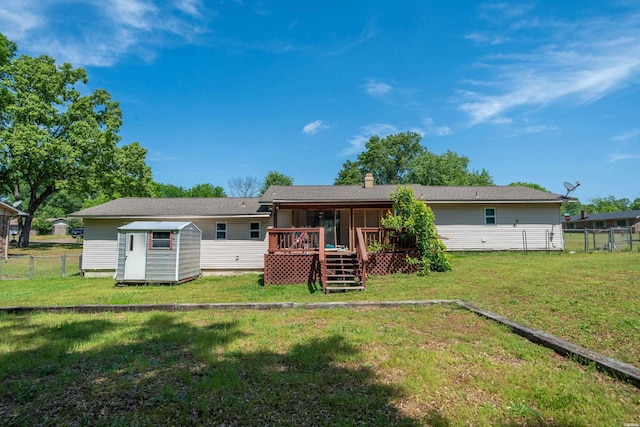 back of house featuring an outdoor structure, fence, a deck, a lawn, and a storage shed
