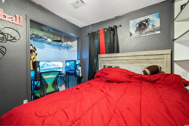 bedroom featuring a textured ceiling, a textured wall, and visible vents