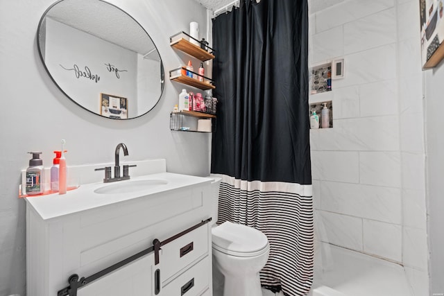 full bathroom with vanity, a tile shower, and toilet