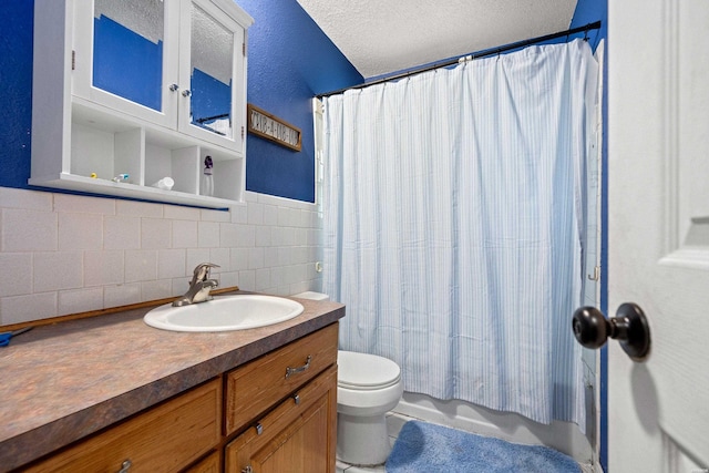 bathroom with vanity, shower / bath combo with shower curtain, toilet, and tile walls