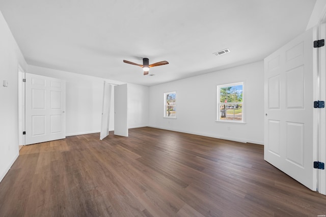 unfurnished bedroom featuring dark wood-style floors, baseboards, visible vents, and a ceiling fan