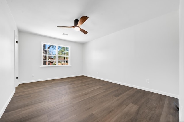 spare room with dark wood-style floors, ceiling fan, visible vents, and baseboards