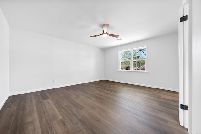 unfurnished room with dark wood-style floors, visible vents, ceiling fan, and baseboards